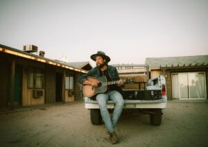 Man with guitar sitting on the truck