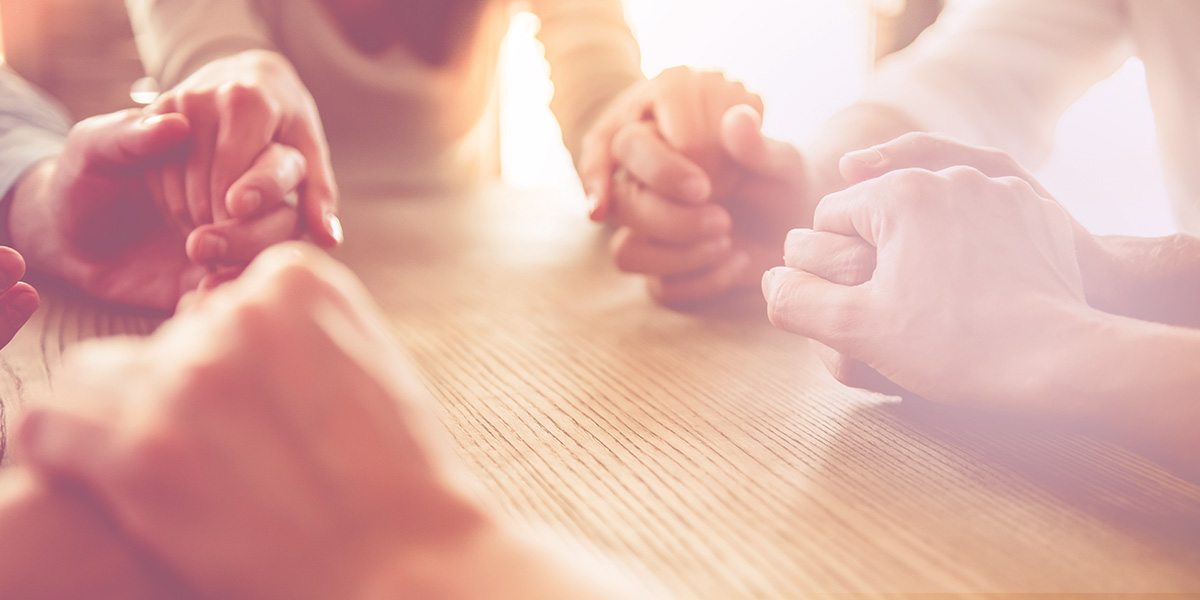 A group of people holding hands and praying