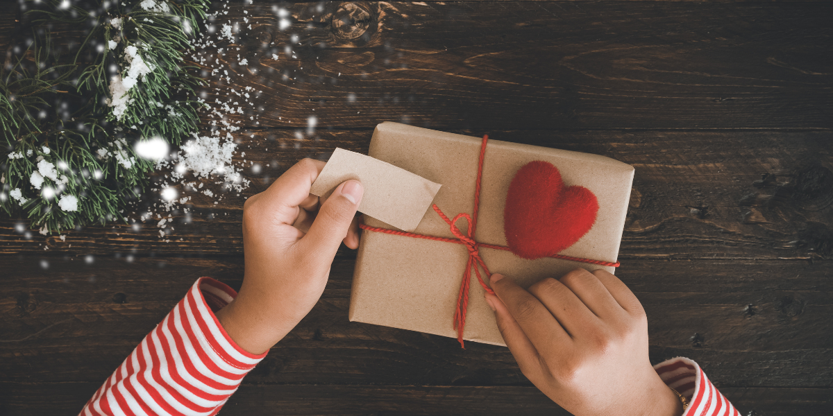 A person making the final touches on wrapping a Christmas gift.