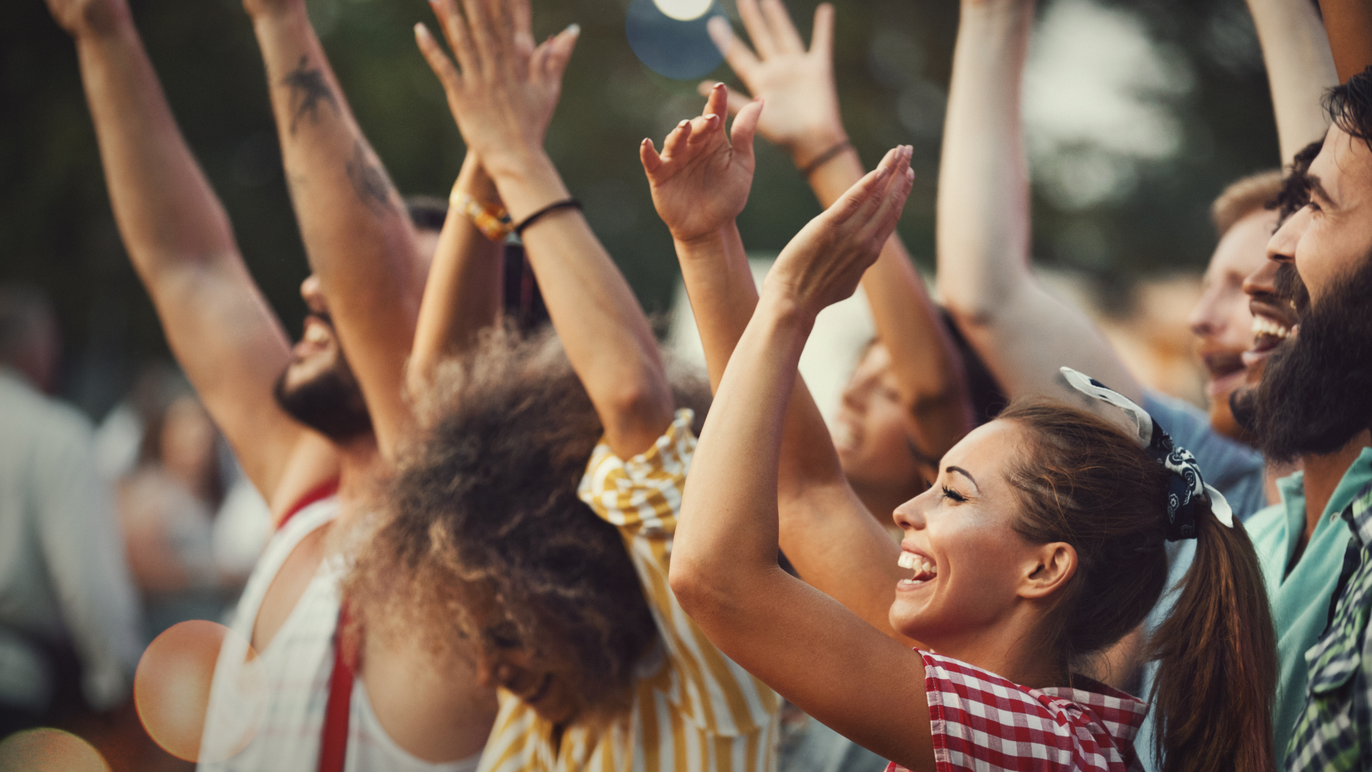 People dancing and having a good time at a concert with their hands raised.